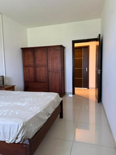 a bedroom with a bed and a wooden cabinet at Le Meritt Appartments in Quatre Bornes