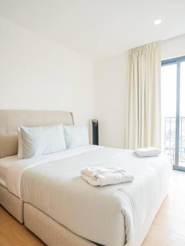 a white bed with white sheets and pillows on it at Luxury 2BR with Pool, Gym & Coworking in Mexico City