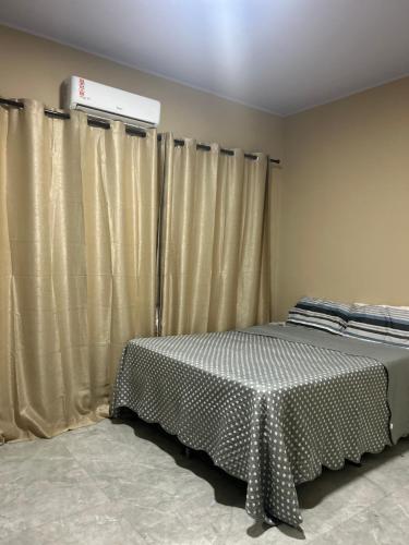 a bedroom with a bed with a table and curtains at Casa Morada Nobre2 in Barreirinhas