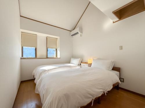 two beds in a white room with two windows at Kijima Base in Kijimadaira