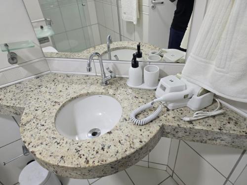 a bathroom counter with a sink and a phone at Flat Biarritz - Praia Litorânea in São Luís
