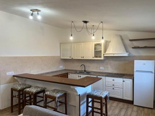 een keuken met witte kasten en een eiland met barkrukken bij Cozy And Cool Flat in Orosei