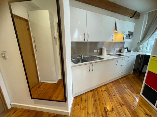 a kitchen with white cabinets and a wooden floor at Heart of Notts, Corner Top View Modern & Cosy Studio in Nottingham