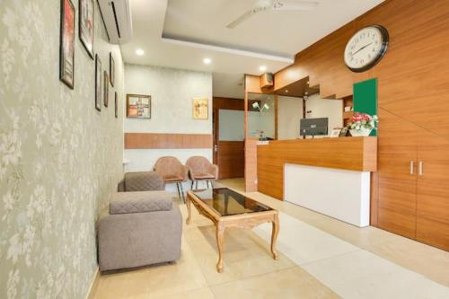 ein Wohnzimmer mit einer Couch und einer Uhr an der Wand in der Unterkunft Hotel Arjun Near Sector 20 Panchkula in Rāmgarh