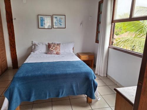 een slaapkamer met een bed met een blauwe deken bij Casa 4 Quartos 2 Quadras da Praia Com Roupa Cama in Porto Seguro