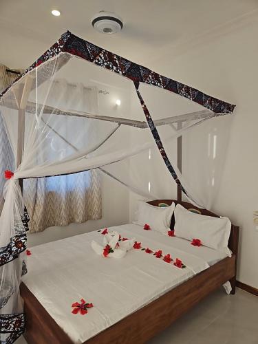 a bedroom with a bed with red flowers on it at Upole HOTEL in Nungwi