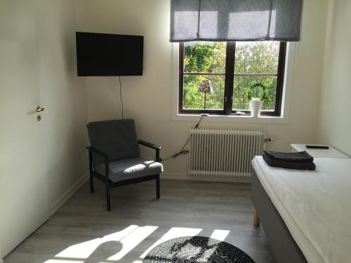 ein Wohnzimmer mit einem Stuhl und einem TV in der Unterkunft Degerfors Bed & Breakfast in Degerfors