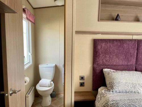 ein kleines Badezimmer mit Toilette und Bett in der Unterkunft Lake Front 2 Bed Caravan, South Cerney in Cirencester