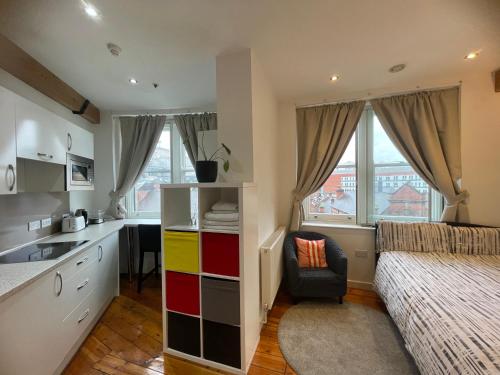 a bedroom with a bed and a kitchen with a sink at Heart of Notts, Corner Top View Modern & Cosy Studio in Nottingham