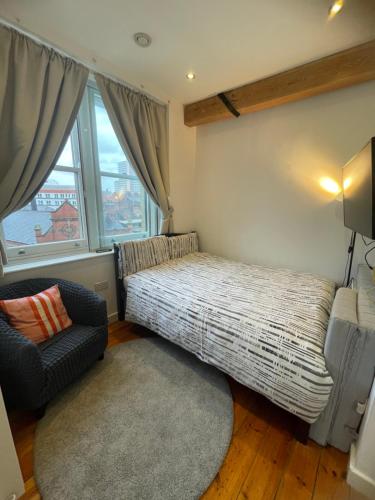a bedroom with a bed and a chair and window at Heart of Notts, Corner Top View Modern & Cosy Studio in Nottingham