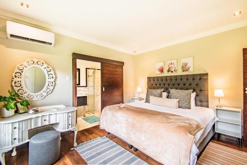 een slaapkamer met een bed, een bureau en een spiegel bij Robyns Nest Self Catering Cottage No4 in Gillitts