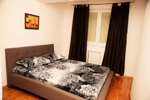 a bed in a bedroom with black curtains and a window at Exclusive Skopje Apartments in Skopje