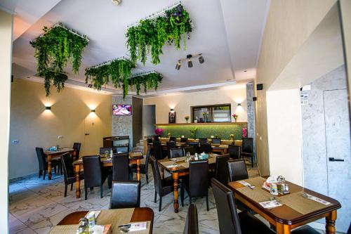 ein Restaurant mit Holztischen, Stühlen und Pflanzen in der Unterkunft Pensiunea Domneasca in Piteşti