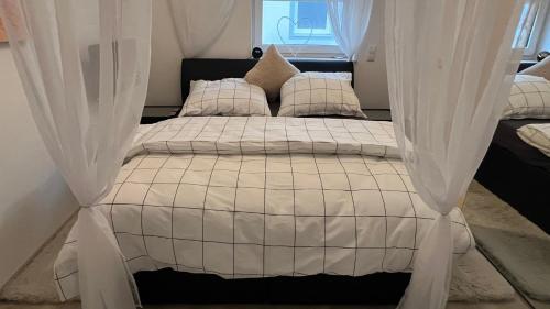 a bed with white curtains in a bedroom at FeWo-Brombachseeblick in Absberg