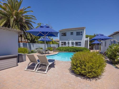 een patio met stoelen en parasols naast een zwembad bij Southeaster in Bloubergstrand