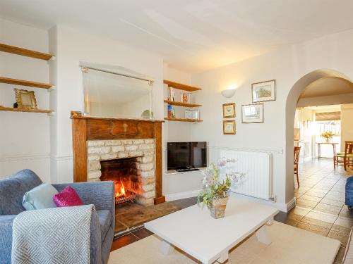 a living room with a fireplace and a blue couch at Jack's Cottage in Tinwell