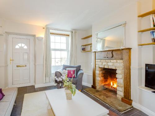 a living room with a fireplace and a couch at Jack's Cottage in Tinwell