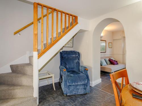 a stairway with a blue chair in a living room at Jack's Cottage in Tinwell