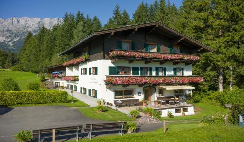 a large white building with flowers on the balconies at otto steiner appartements pension ellmau & wilder kaiser in Ellmau