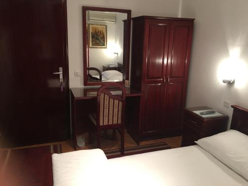 a bedroom with a bed and a desk and a mirror at Vila Lux Milikic in Kraljevo