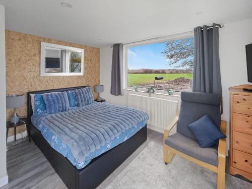 Meysey HamptonLakeview at The Hideaway的一间卧室，里面有一张床、一把椅子和一扇窗户。