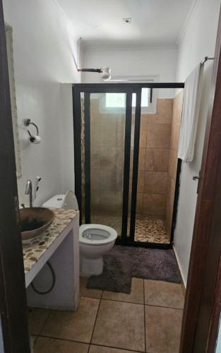 a bathroom with a shower and a toilet and a sink at GREEN House in Vila Praia Do Bilene