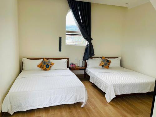 two white beds in a room with a window at Khách Sạn Trung Loan in Ninh Hải