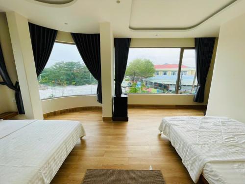 a bedroom with two beds and a large window at Khách Sạn Trung Loan in Ninh Hải