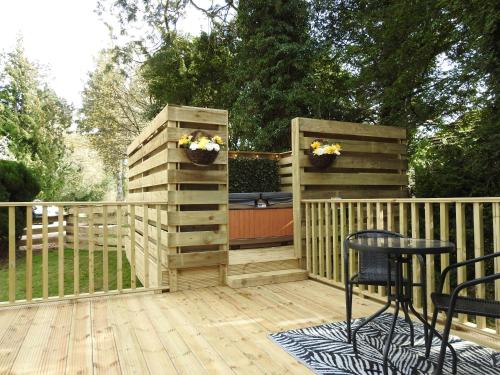 een houten terras met 2 stoelen en een hek bij Cear 2- Private Hot Tub- Perth-Pet Friendly Lodge in Almondbank