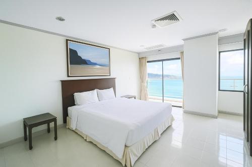 a bedroom with a white bed and a large window at Patong Beachfront Tower 30 Floor Penthouse in Patong Beach