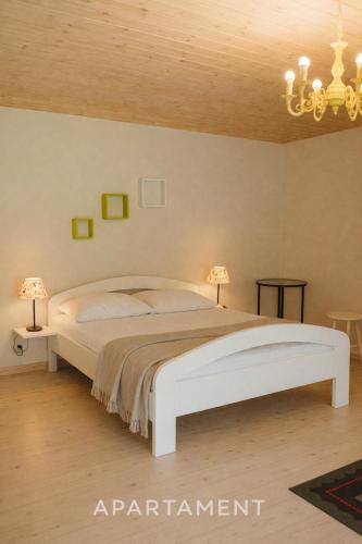 a bedroom with a white bed and a chandelier at Domek w Dolinie Drwęcy in Lubicz