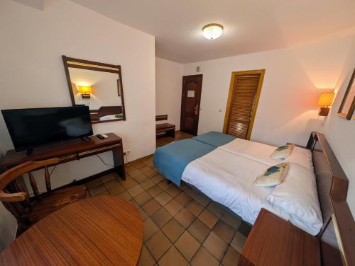 ein Schlafzimmer mit einem Bett und einem Schreibtisch mit einem Fernseher in der Unterkunft Hotel Santa María in Palos de la Frontera