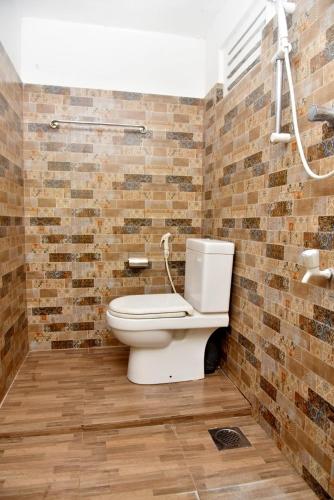 a bathroom with a toilet and a brick wall at Sunils Inn Bentota in Bentota