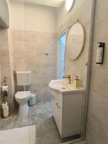 a bathroom with a sink and a toilet and a mirror at GrandPa Delux in Miskolc