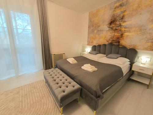 a bedroom with a large bed with a bench next to it at GrandPa Delux in Miskolc