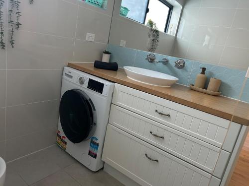 a washing machine in a bathroom with a sink at The Seaview at Semaphore Park in Port Adelaide