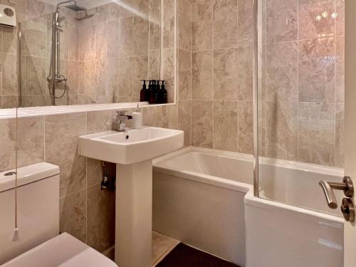 a bathroom with a sink and a tub and a toilet at Stylish 1 Bedroom Apartment with Free Parking and Links to London & Essex in Stifford