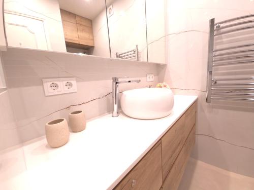 ein weißes Badezimmer mit Waschbecken und Spiegel in der Unterkunft Caparica Escape By Gt House in Costa da Caparica