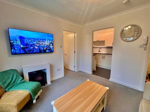 a living room with a couch and a tv on the wall at Stylish 1 Bedroom Apartment with Free Parking and Links to London & Essex in Stifford