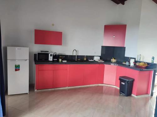 a kitchen with red cabinets and a white refrigerator at Appartement avec vue mer à Capesterre-Belle-Eau in Capesterre-Belle-Eau