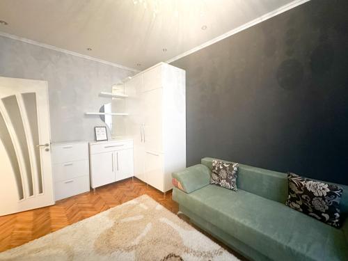 uma sala de estar com um sofá verde e uma cozinha em Central City Puskin Street em Chişinău