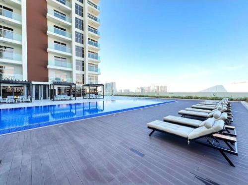 a swimming pool with chaise lounge chairs next to a building at Fully Equipped Home near Miracle & Butterfly Gardens in Dubai