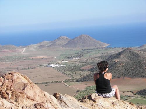 a woman sitting on top of a rock looking at the mountains at Cala Chica Cabo de Gata in Las Negras