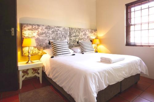 una camera da letto con un letto con lenzuola e cuscini bianchi di Swellendam Self Catering a Swellendam