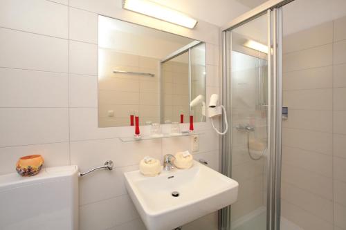 a white sink sitting under a mirror in a bathroom at Panorama Landhaus in Saalbach-Hinterglemm