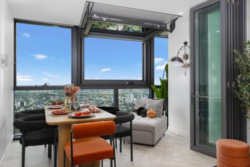 a living room with a table and chairs and large windows at Luxury 50th Floor 2BR at Queens Wharf with Parking in Brisbane