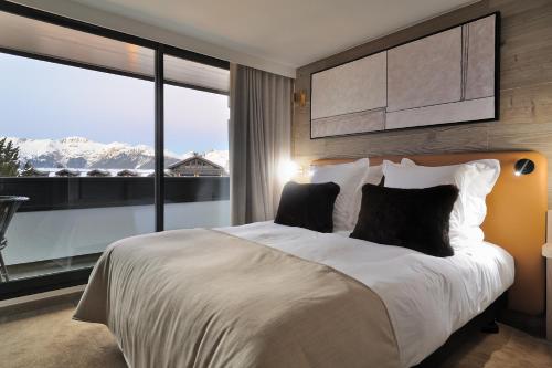 ein Schlafzimmer mit einem großen Bett und einem großen Fenster in der Unterkunft La Résidence Belledonne in Courchevel