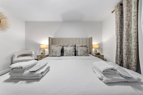 a white bedroom with a large bed and a chair at New Modern Hybrid 4 Bedrooms 7 Bed apartment 12 guest capacity in London