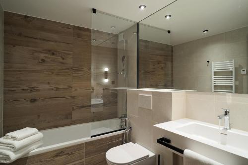 ein Badezimmer mit Waschbecken, Toilette und Spiegel in der Unterkunft La Résidence Belledonne in Courchevel
