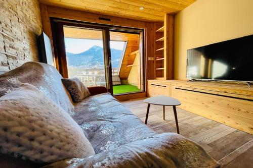 Una sala de estar con un sofá y un televisor grande. en Beautiful studio with magnificent view, en Briançon